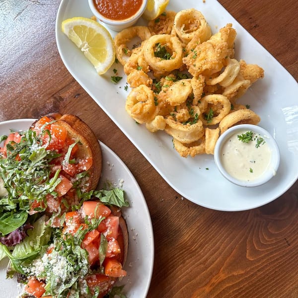 Plates of golden fried calamari with lemon and marinara, and bruschetta with tomatoes and greens.
