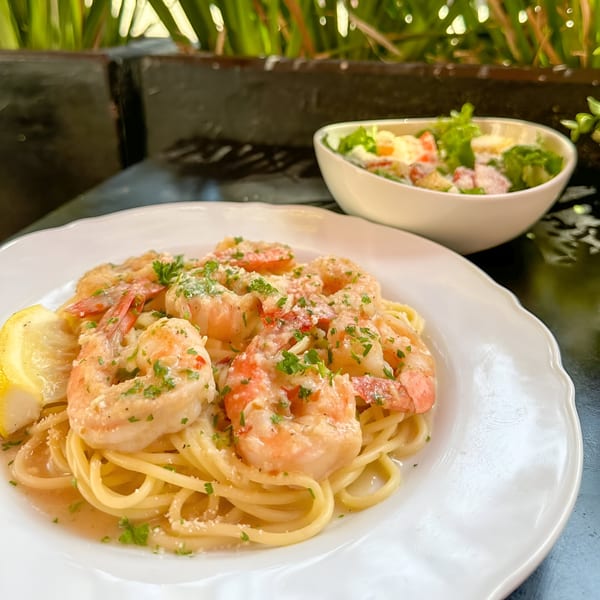 Petrini's shrimp scampi with spaghetti, lemon, and parsley, served with a side salad.