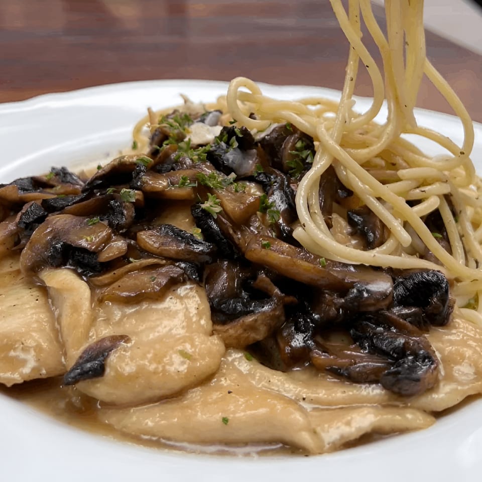 Petrini's chicken marsala with mushrooms and spaghetti being twirled on a fork.