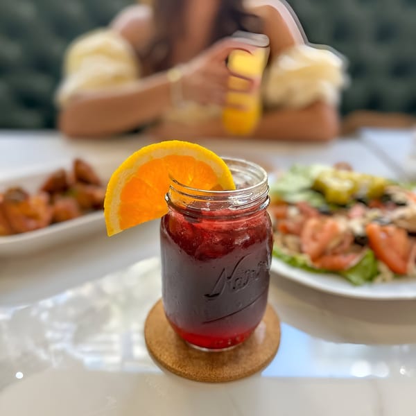 A Petrini's Italian restaurant table with a drink, salad, and a person in the background.
